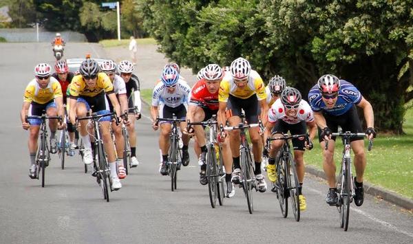Jason Thomason (yellow jersey with black trim and no number on helmet, Michael Jones (19) and Mel Titter (26) cross safely in the front bunch to maintain their top three placings.